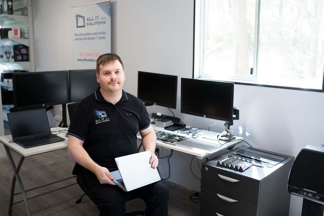 All I.T. Solutions (QLD) technician in Jimboomba workshop holding a laptop